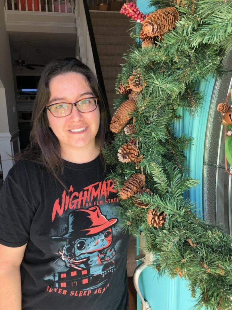 A woman standing next to a christmas wreath.