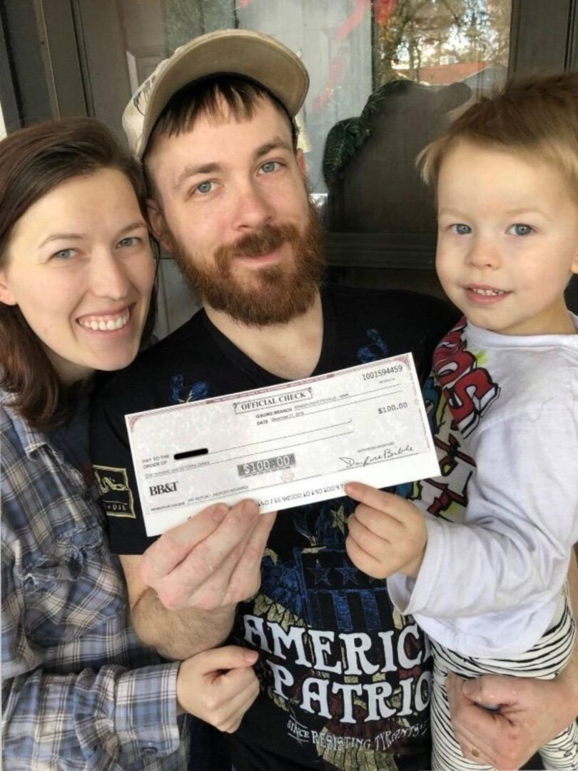 A man and woman holding a check with a child.
